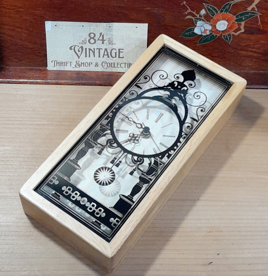 Vintage Decorative Clock (Category: Clocks) located in Las Pinas. Submitted by 84vintage (Listing ID 1427102251, Image 2). Description: Great gift item for House warming or a wedding. Cost effective with nice impact. Vintage clock features a unique design with a black decorative overlay on a light-colored wooden frame. The clock face displays Roman numerals. Actual photos posted. Please examine them carefully as they are part of the description. 