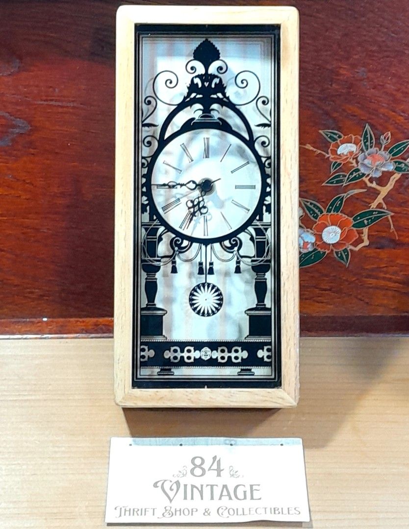 Vintage Decorative Clock (Category: Clocks) located in Las Pinas. Submitted by 84vintage (Listing ID 1427102251, Image 1). Description: Great gift item for House warming or a wedding. Cost effective with nice impact. Vintage clock features a unique design with a black decorative overlay on a light-colored wooden frame. The clock face displays Roman numerals. Actual photos posted. Please examine them carefully as they are part of the description. 