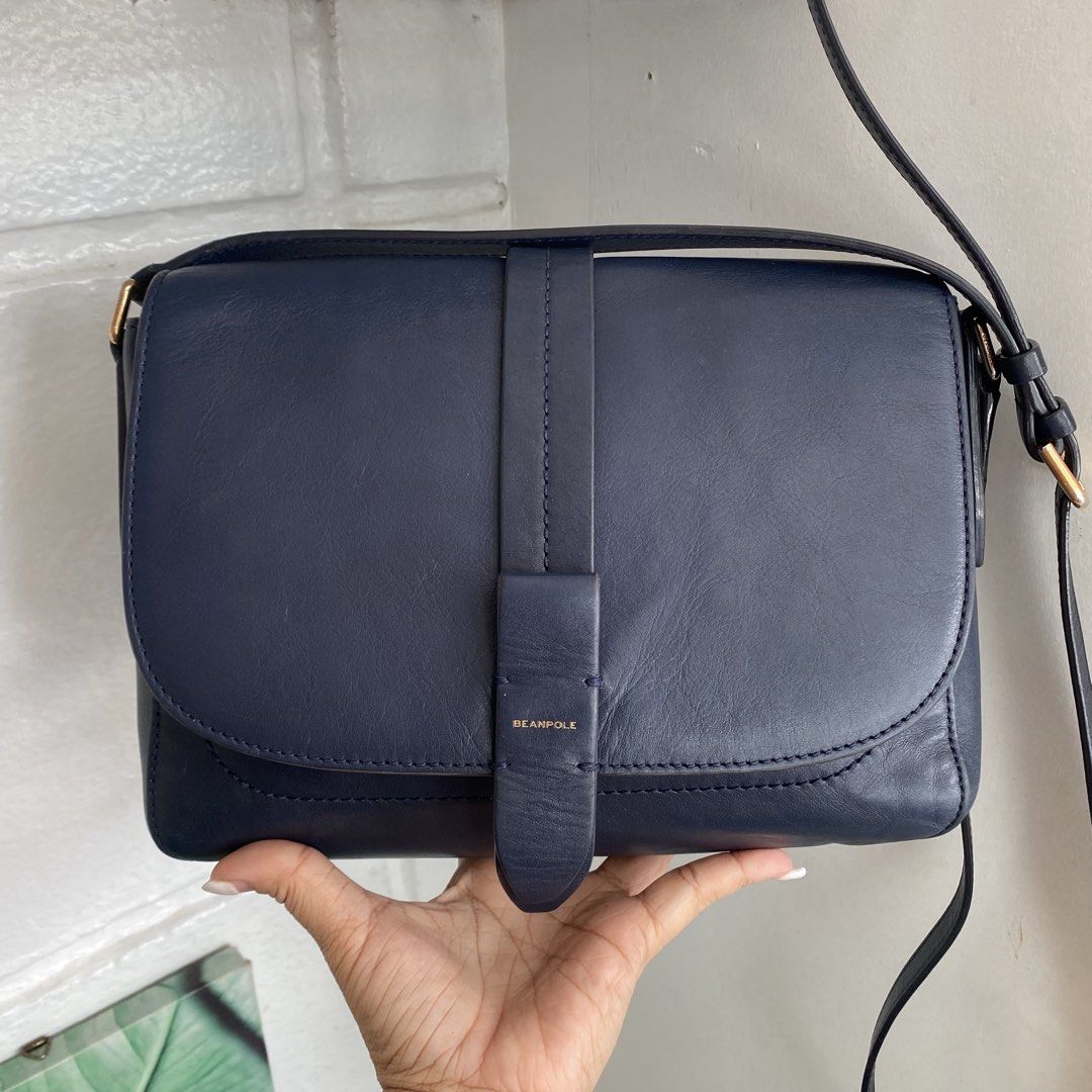 Beanpole Navy Blue Crossbody Bag (Category: Cross-body Bags) located in Roxas City. Submitted by rglnos (Listing ID 1427197006, Image 1). Description: Navy blue crossbody bag from Beanpole. Features a flap closure with a strap detail. The bag has a gold-tone hardware and an adjustable shoulder strap. The interior has a zippered pocket and a brand label..