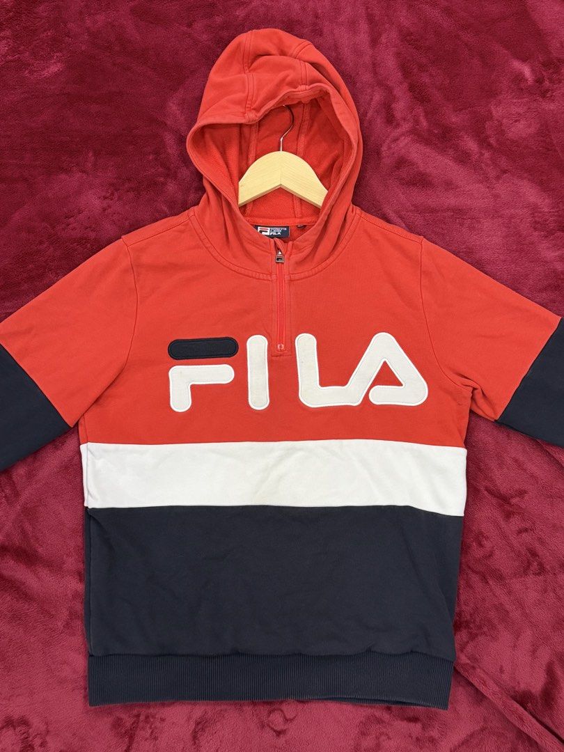 Fila Hoodie with Hood (Category: Hoodies) located in Manila. Submitted by branded_preloved14 (Listing ID 1427309397, Image 1). Description: Fila hoodie with a red, white, and navy color block design. Features a half-zip closure and the Fila logo on the front. The hoodie has a hood and long sleeves. The size tag indicates 165/84A. The material composition is 89% cotton and 11% spandex. 24x18.5 inches.