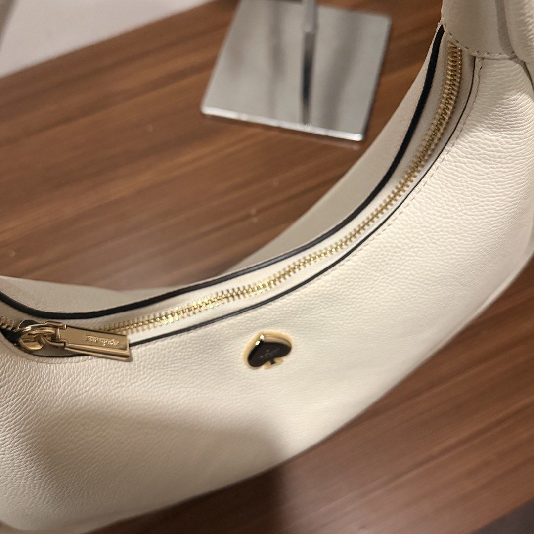 Kate Spade Cream Shoulder Bag (Category: Luxury Bags & Wallets) located in San Pedro. Submitted by love.bruce10 (Listing ID 1427275087, Image 3). Description: Cream-colored shoulder bag from Kate Spade. Features a gold zipper and a gold spade logo. The interior is cream-colored. The bag has a rounded shape and a single shoulder strap. The bag is new with tags. Used a few times only, bought in the US.