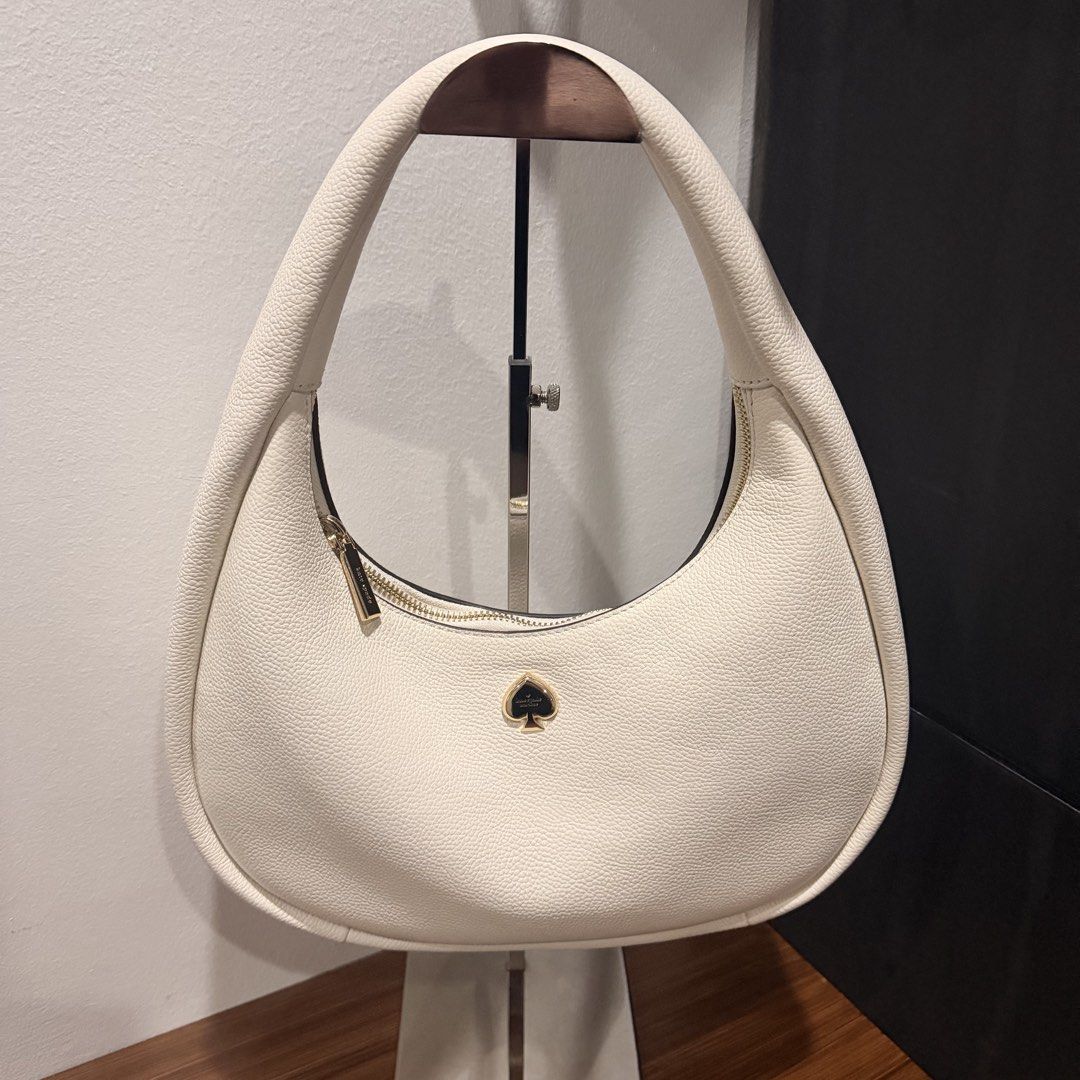 Kate Spade Cream Shoulder Bag (Category: Luxury Bags & Wallets) located in San Pedro. Submitted by love.bruce10 (Listing ID 1427275087, Image 1). Description: Cream-colored shoulder bag from Kate Spade. Features a gold zipper and a gold spade logo. The interior is cream-colored. The bag has a rounded shape and a single shoulder strap. The bag is new with tags. Used a few times only, bought in the US.