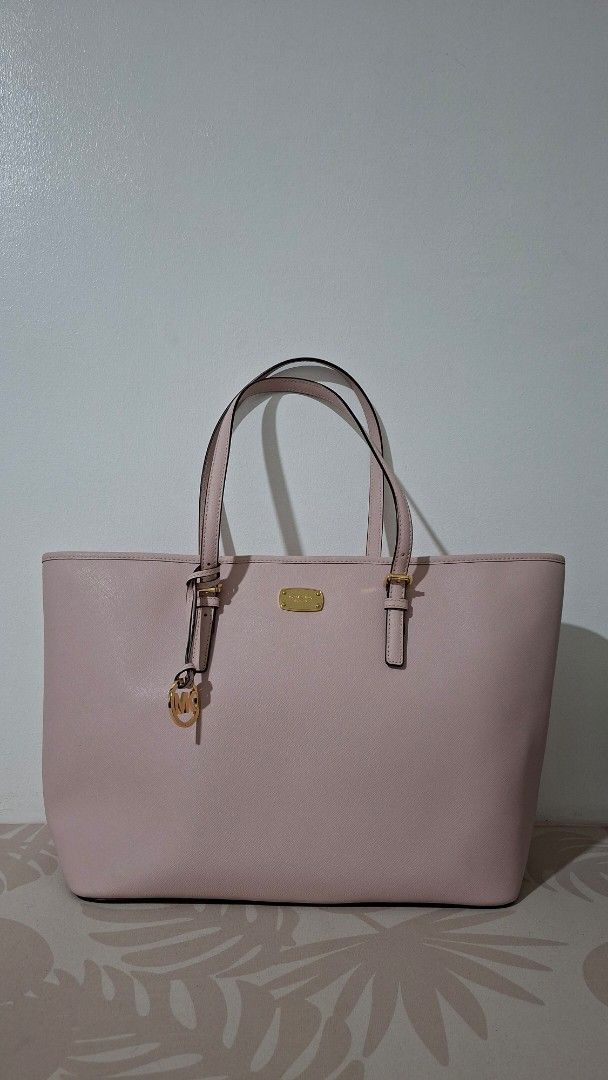 Michael Kors Pink Tote Bag (Category: Luxury Bags & Wallets) located in Imus. Submitted by pick_and_dig (Listing ID 1427311196, Image 1). Description: Michael Kors tote bag is in a soft pink color. It features a spacious interior with multiple pockets, including a zippered compartment. The bag has double handles and gold-tone hardware. The interior lining is patterned with the Michael Kors logo. MOP: GCash, Maya Free delivery within the Philippin