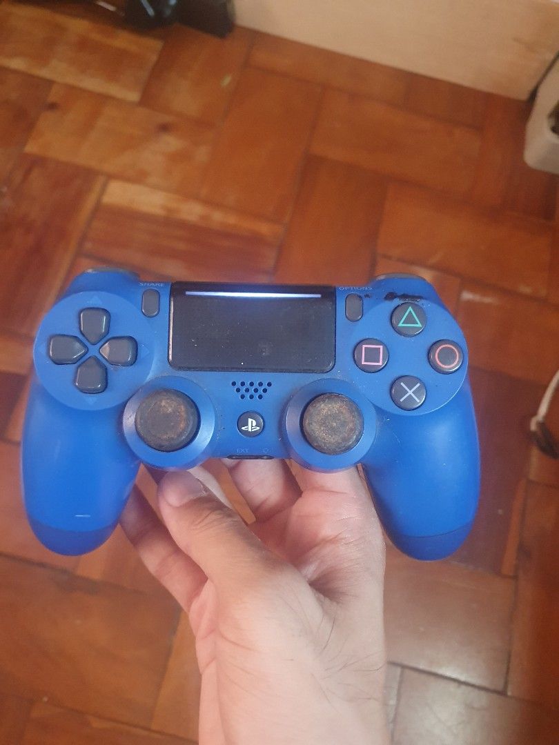 Sony PlayStation 4 Controller (Category: Controllers) located in San Pablo. Submitted by happyflower_4a9f30 (Listing ID 1427177914, Image 2). Description: Blue and black Sony PlayStation 4 controllers. The blue controller has some wear on the thumbsticks. The black controller has a visible crack on the side. Both controllers have the standard PlayStation button layout and a touchpad. The controllers are in working condition..