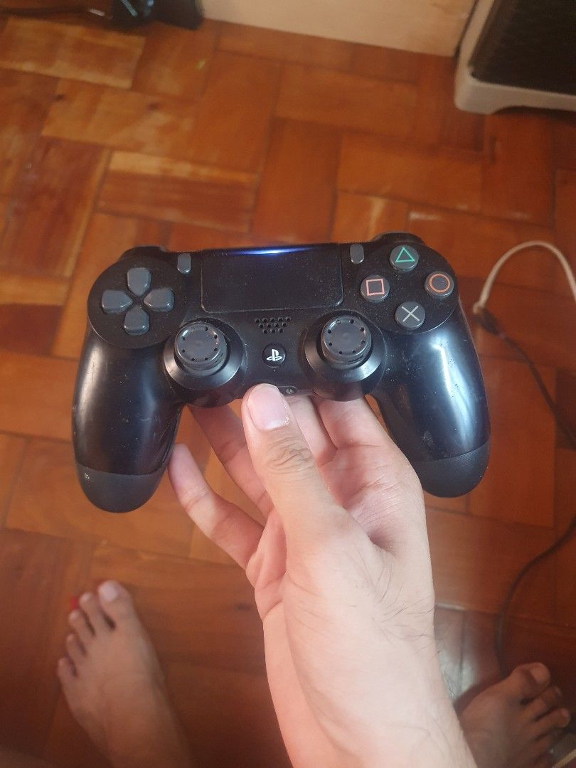 Sony PlayStation 4 Controller (Category: Controllers) located in San Pablo. Submitted by happyflower_4a9f30 (Listing ID 1427177914, Image 3). Description: Blue and black Sony PlayStation 4 controllers. The blue controller has some wear on the thumbsticks. The black controller has a visible crack on the side. Both controllers have the standard PlayStation button layout and a touchpad. The controllers are in working condition..