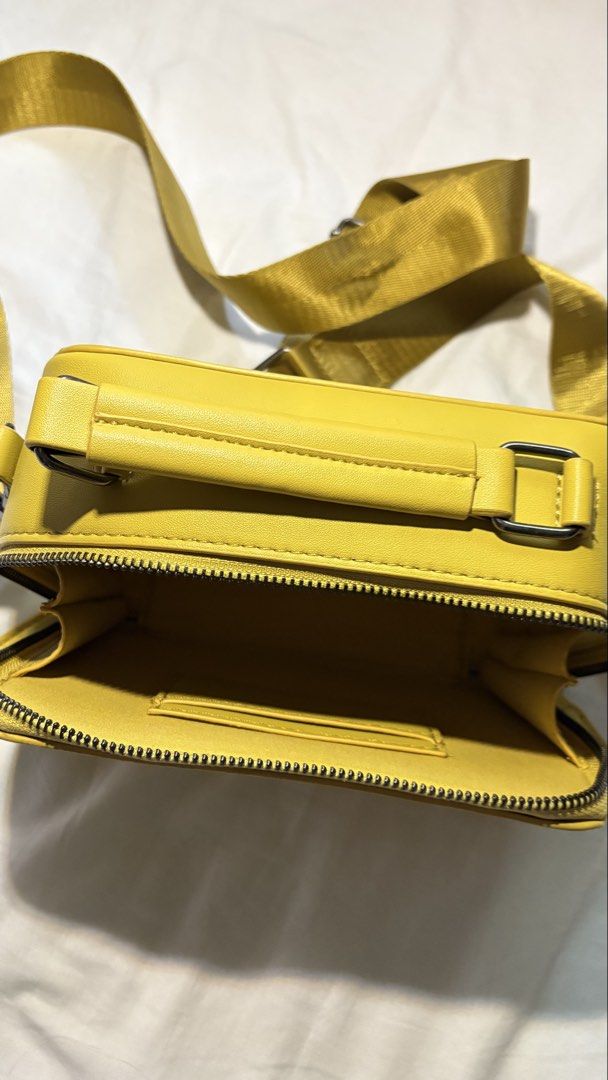 Straight Forward Yellow Crossbody Bag (Category: Cross-body Bags) located in Manila. Submitted by thirteen_preloved (Listing ID 1427182626, Image 3). Description: Bright yellow crossbody bag with a top handle and a detachable shoulder strap. The bag features a rectangular shape with a zipper closure. The brand name "STRAIGHT FORWARD" is visible on the front. The interior is lined with a matching yellow fabric. The bag has metal feet on the bottom