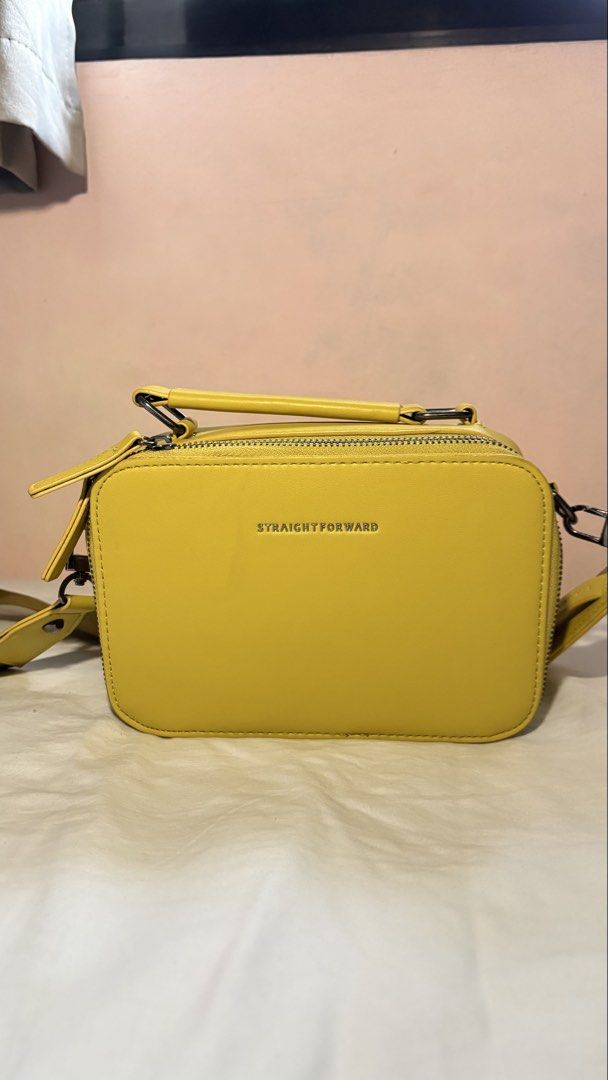 Straight Forward Yellow Crossbody Bag (Category: Cross-body Bags) located in Manila. Submitted by thirteen_preloved (Listing ID 1427182626, Image 1). Description: Bright yellow crossbody bag with a top handle and a detachable shoulder strap. The bag features a rectangular shape with a zipper closure. The brand name "STRAIGHT FORWARD" is visible on the front. The interior is lined with a matching yellow fabric. The bag has metal feet on the bottom