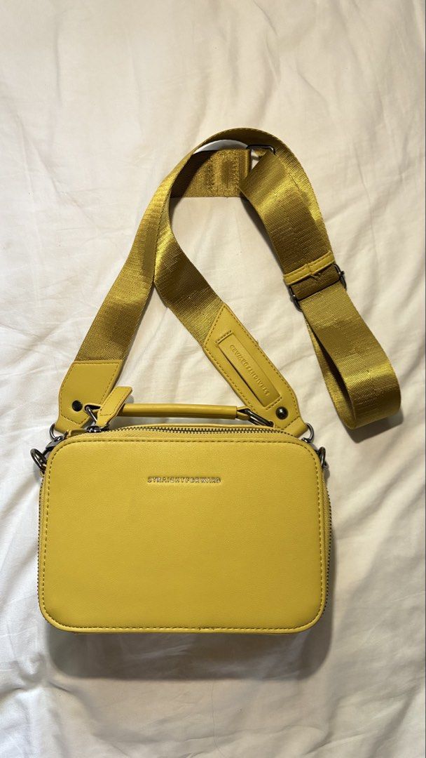 Straight Forward Yellow Crossbody Bag (Category: Cross-body Bags) located in Manila. Submitted by thirteen_preloved (Listing ID 1427182626, Image 2). Description: Bright yellow crossbody bag with a top handle and a detachable shoulder strap. The bag features a rectangular shape with a zipper closure. The brand name "STRAIGHT FORWARD" is visible on the front. The interior is lined with a matching yellow fabric. The bag has metal feet on the bottom