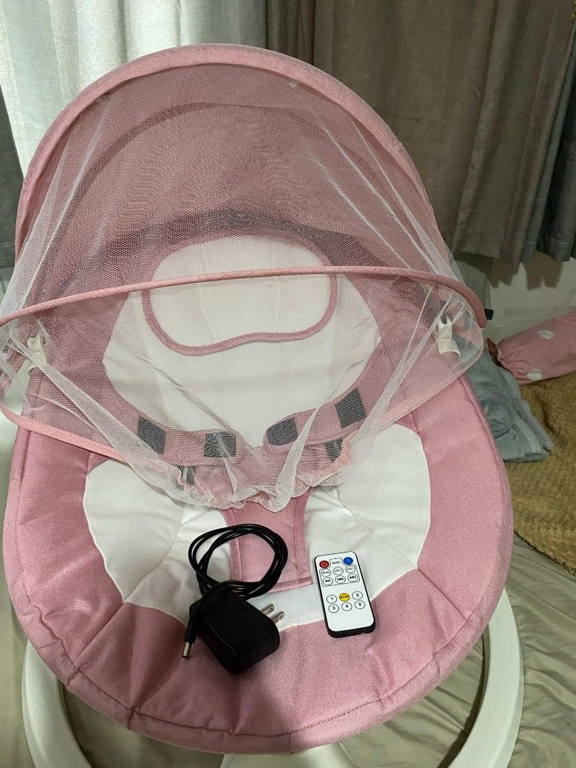 Topborn Baby Swing Rocker Cradle (Category: Cots & Cribs) located in Caloocan City. Submitted by moonstarrr05925 (Listing ID 1427242452, Image 2). Description: Electric adjustable baby rocking chair with a pink canopy and mosquito net. Includes a remote control and power adapter. Features a white base with control buttons. The seat is pink and white with safety straps. Suitable for babies..