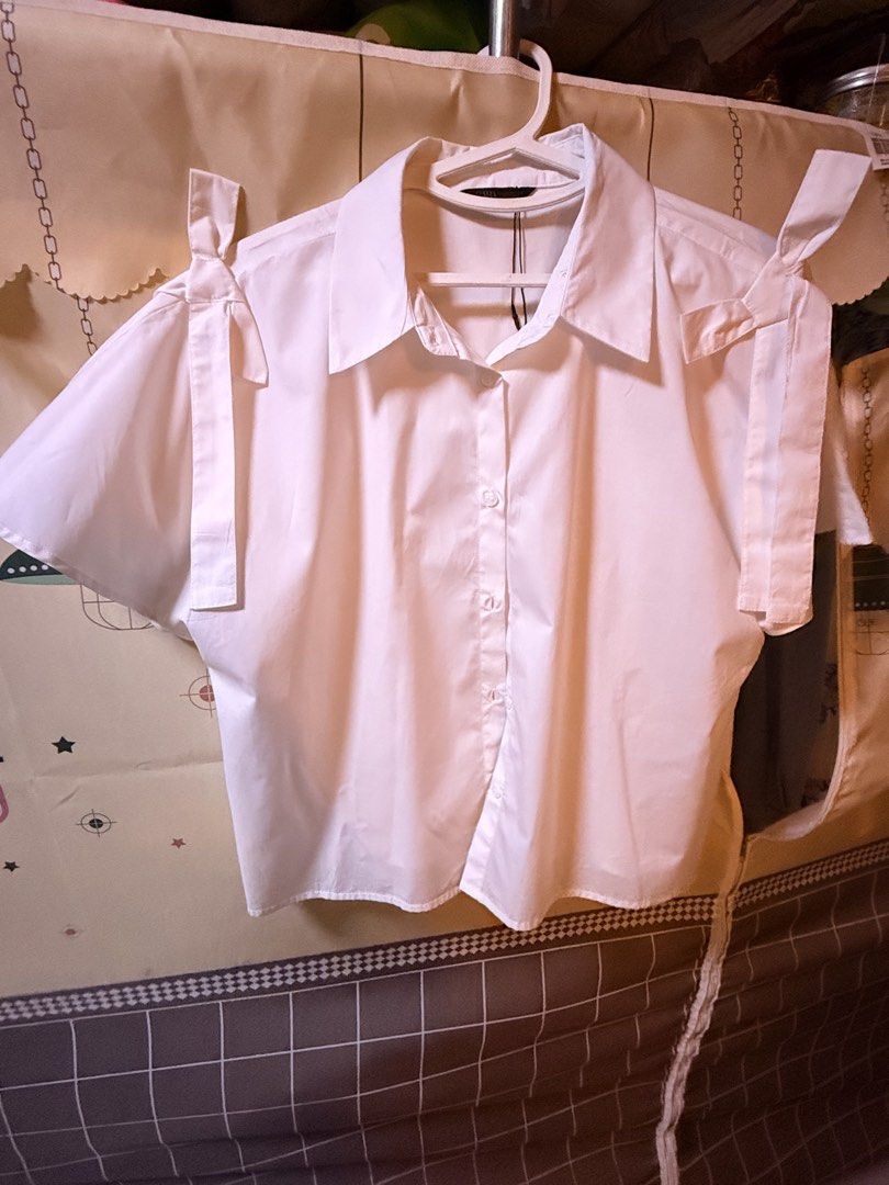 Zara White Shoulder Tie Blouse (Category: Blouses) located in Cainta. Submitted by Kamilerloo (Listing ID 1427251696, Image 3). Description: White blouse with short sleeves and shoulder ties. Features a collared neckline and button-down front. The blouse has a relaxed fit. Perfect for a casual yet stylish look. Poplin shirt with a ribbon detail from ZARA..