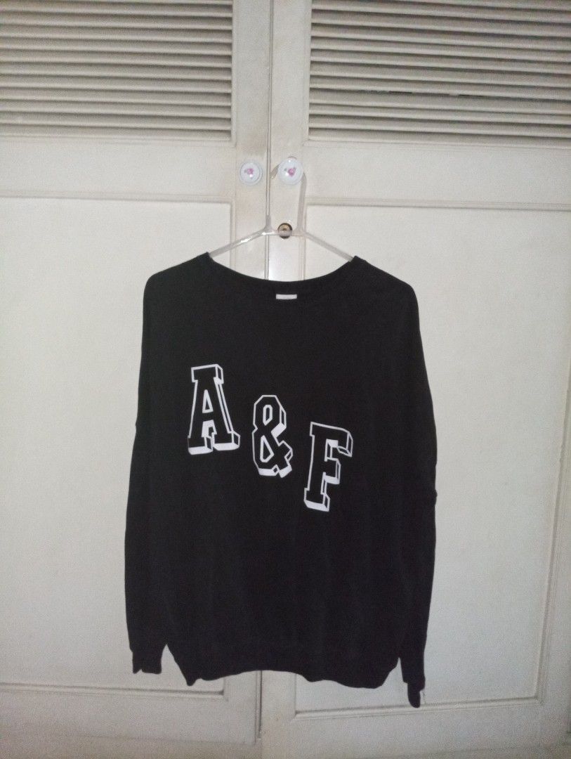 Abercrombie & Fitch Black Sweatshirt (Category: Longsleeves) located in Paranaque City. Submitted by krispywispy (Listing ID 1427349254, Image 1). Description: Black Abercrombie & Fitch sweatshirt with white lettering. Features the brand's logo on the front. It is hanging on a hanger against a white background..