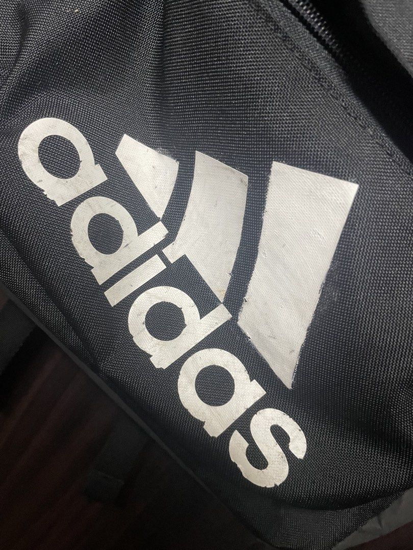 Adidas Backpack (Category: Backpacks) located in Manila. Submitted by ynot0615 (Listing ID 1427353008, Image 2). Description: Adidas backpack in black. Features a main compartment, a front pocket, and side pockets. The Adidas logo is prominently displayed on the front. Includes a zipper closure. Made in Indonesia. The interior has a tag with a QR code and size information. Need wash Declutter .