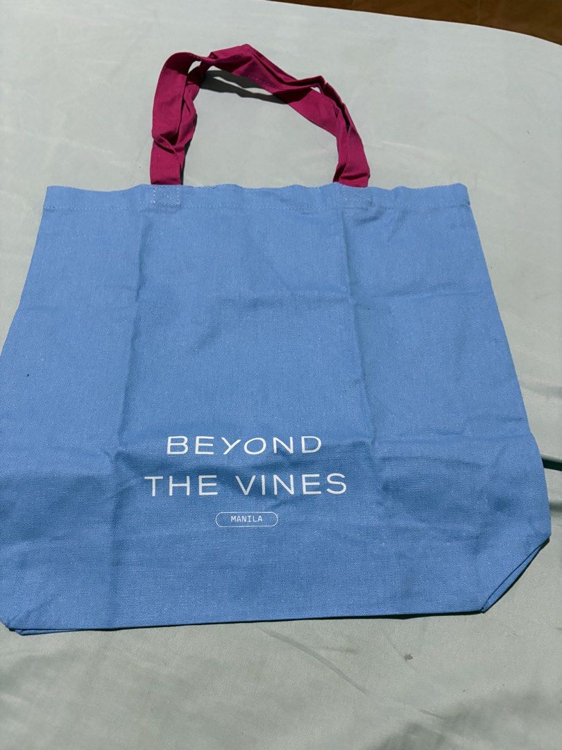 Beyond The Vines Manila Tote Bag (Category: Tote Bags) located in Quezon City. Submitted by brandedthingsforless (Listing ID 1427438063, Image 1). Description: Beyond The Vines tote bag features a blue body with magenta handles. The front of the bag displays the brand name and "Manila". The back of the bag has a design and the text "GOOD DESIGN ACCESSIBLE TO ALL". It is made of a sturdy material and is perfect for everyday use..