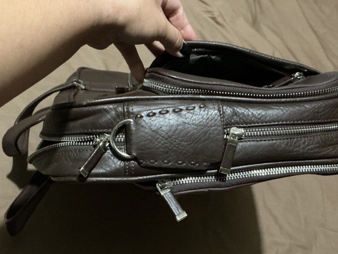 Di Caro Brown Leather Briefcase (Category: Luxury Bags & Wallets) located in Angeles City. Submitted by goodbuysathome (Listing ID 1427432917, Image 3). Description: Di Caro briefcase is made of brown leather. It features a top handle, multiple zippered compartments, and a front pocket. The interior has several pockets and compartments for organization. The bag has a silver-tone zipper and hardware. The brand name is visible on the front and insi