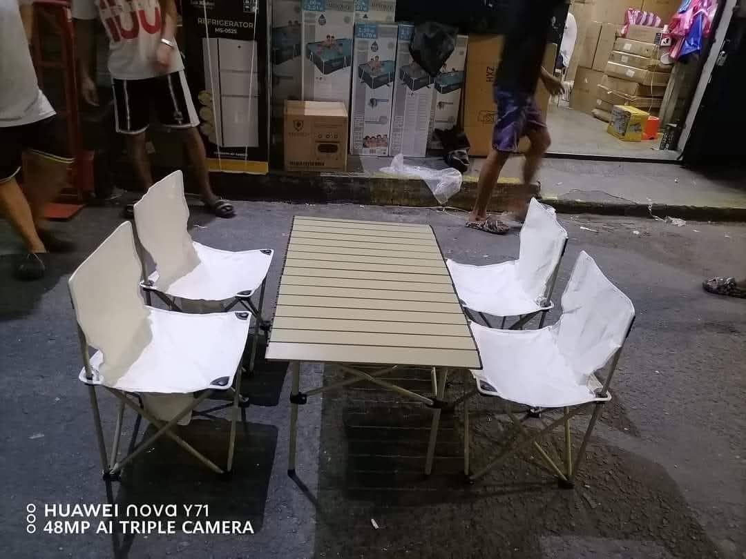 Folding Camping Table and Chairs Set (Category: Everything Else Others) located in Manila. Submitted by jelai.cybyb (Listing ID 1427419774, Image 1). Description: Set includes a folding table and four chairs. The table has a light-colored, slatted top and foldable legs. The chairs have white fabric seats and backs with a foldable metal frame. Perfect for outdoor activities or extra seating..