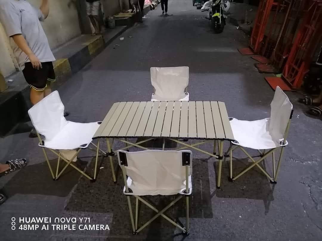 Folding Camping Table and Chairs Set (Category: Outdoor Furniture) located in Manila. Submitted by haideshop (Listing ID 1427419900, Image 2). Description: Set includes a folding table and four chairs. The table has a light-colored, slatted top and foldable legs. The chairs have white fabric seats and backs with a foldable metal frame. Perfect for outdoor activities or small spaces. Easy to set up and store..