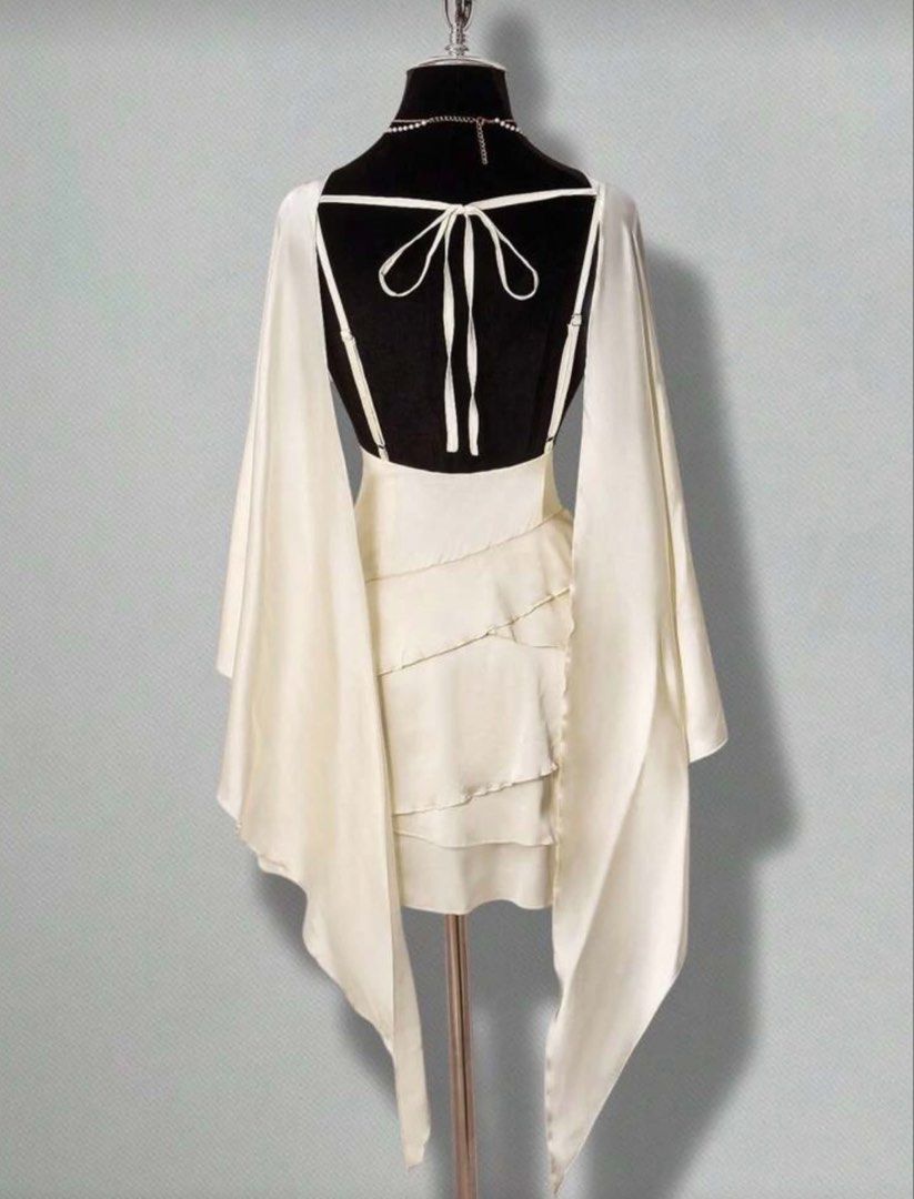 [FOR RENT] Elegant Classy Old Money Chic Sophisticated White Ruffled Mini Dress with Cape Scarf Silk Sleeves (Category: Dresses) located in Pasig City. Submitted by ilovenico (Listing ID 1427335545, Image 2). Description: Elegant white mini dress featuring a layered, ruffled skirt and a unique cape sleeve design. The dress has a fitted bodice and a low back with tie-up details. It includes a delicate necklace. Perfect for special occasions or a s