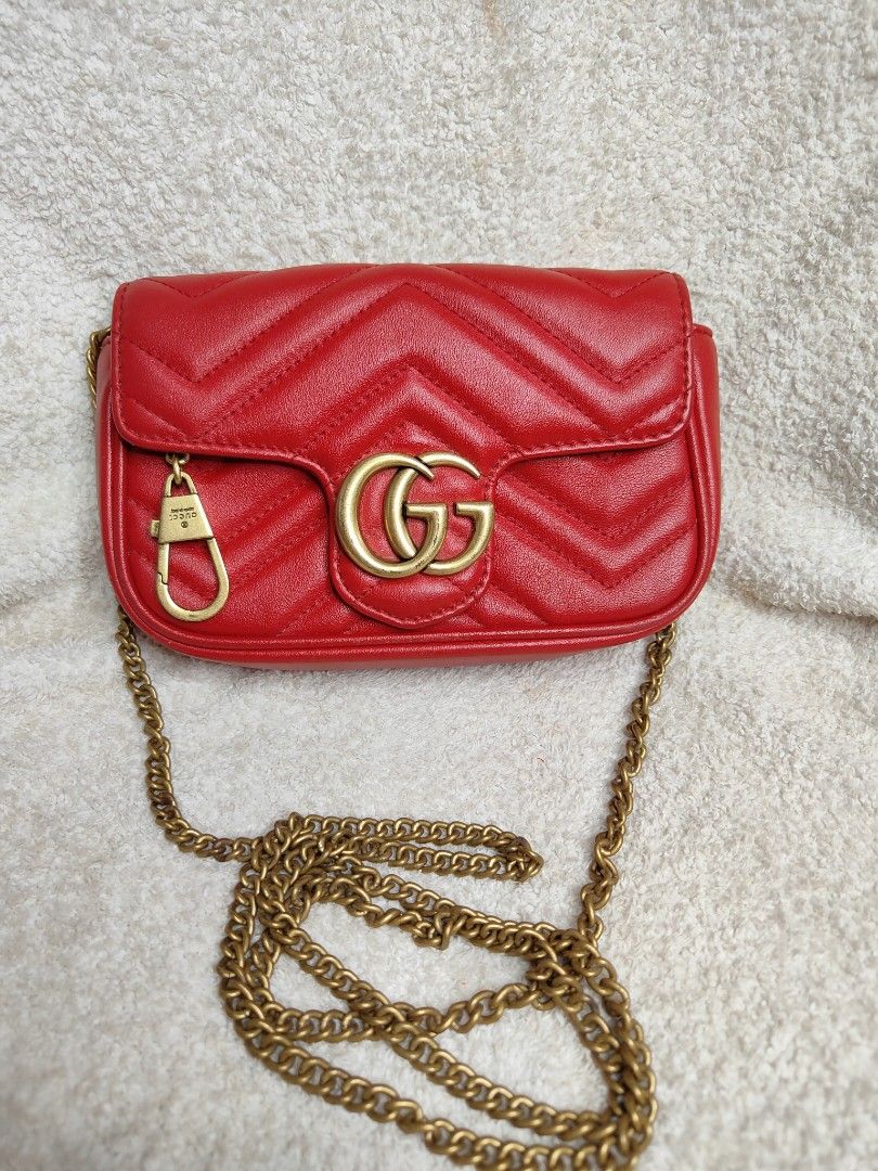 Gucci GG Marmont Super Mini Bag Red (Category: Luxury Bags & Wallets) located in Cebu City. Submitted by cherreymie70208 (Listing ID 1427355465, Image 1). Description: Gucci GG Marmont Super Mini bag in red. Features a chevron quilted design with a heart on the back. Includes a chain strap and a GG logo on the front. The interior has a leather tag with the Gucci logo and serial number. The bag has a snap closure and a gold-tone chain strap..