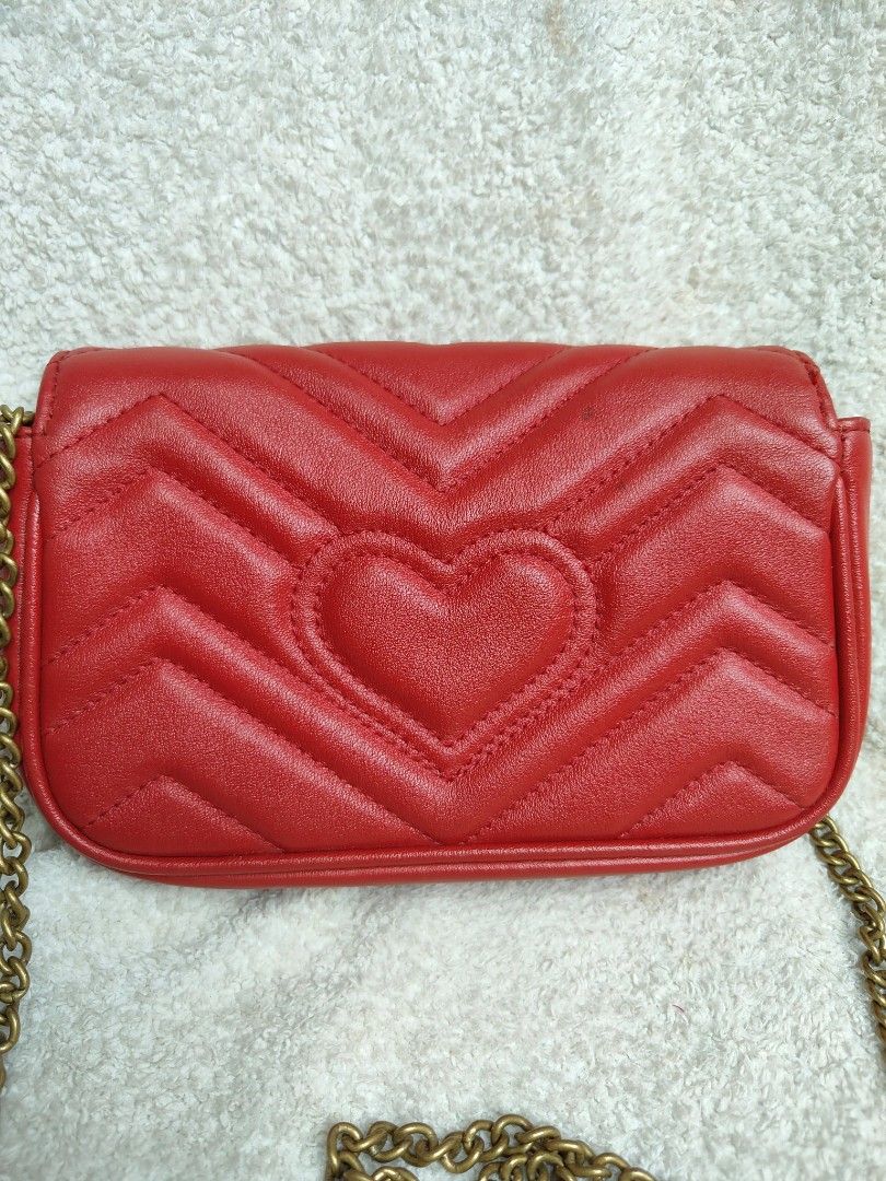 Gucci GG Marmont Super Mini Bag Red (Category: Luxury Bags & Wallets) located in Cebu City. Submitted by cherreymie70208 (Listing ID 1427355465, Image 3). Description: Gucci GG Marmont Super Mini bag in red. Features a chevron quilted design with a heart on the back. Includes a chain strap and a GG logo on the front. The interior has a leather tag with the Gucci logo and serial number. The bag has a snap closure and a gold-tone chain strap..
