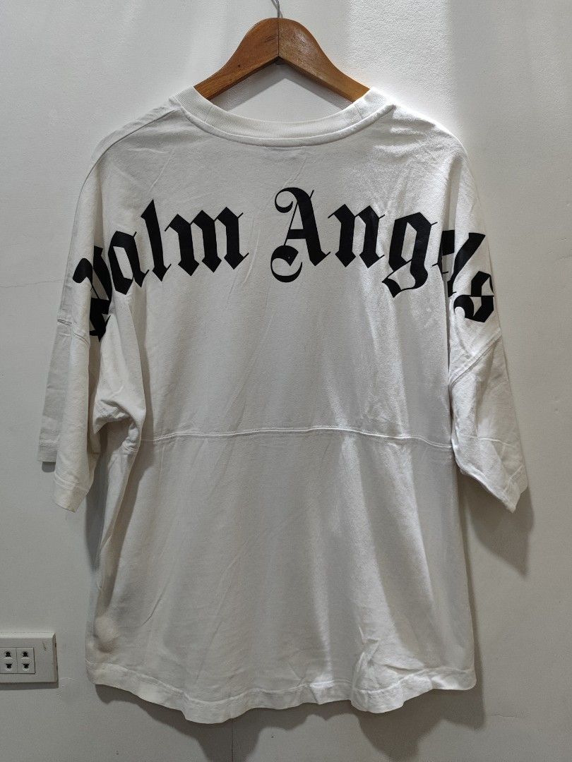 Palm Angels White T-shirt (Category: Tshirts & Polo Shirts ) located in Quezon City. Submitted by trellzilla666 (Listing ID 1427339519, Image 2). Description: White Palm Angels T-shirt with short sleeves. Features the Palm Angels logo on the front collar and the back. The shirt has a unique design with a horizontal seam across the middle. The sleeves have a small black logo on the left sleeve..