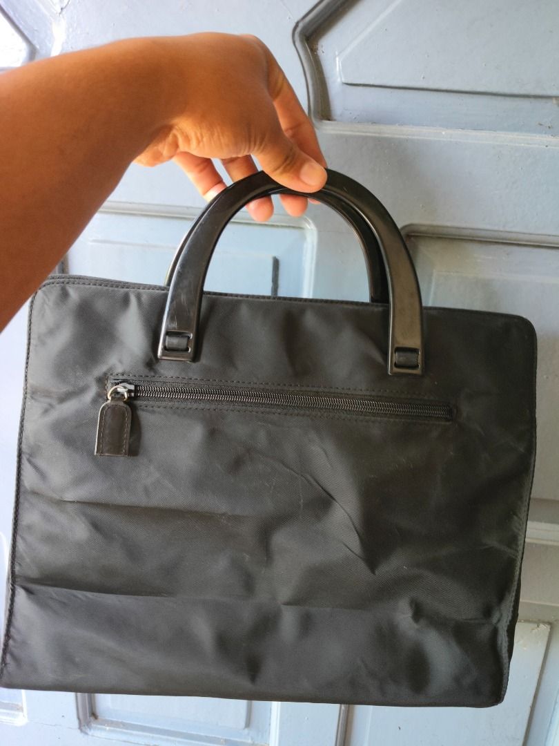 Prada Black Nylon Tote Bag (Category: Luxury Bags & Wallets) located in Caloocan City. Submitted by balizaclar77072 (Listing ID 1427453350, Image 2). Description: Black Prada tote bag. Features a top handle design with a zipper closure on the back. The interior includes a small pocket with a Prada label. The bag has a triangular Prada logo on the front. Made in Italy..