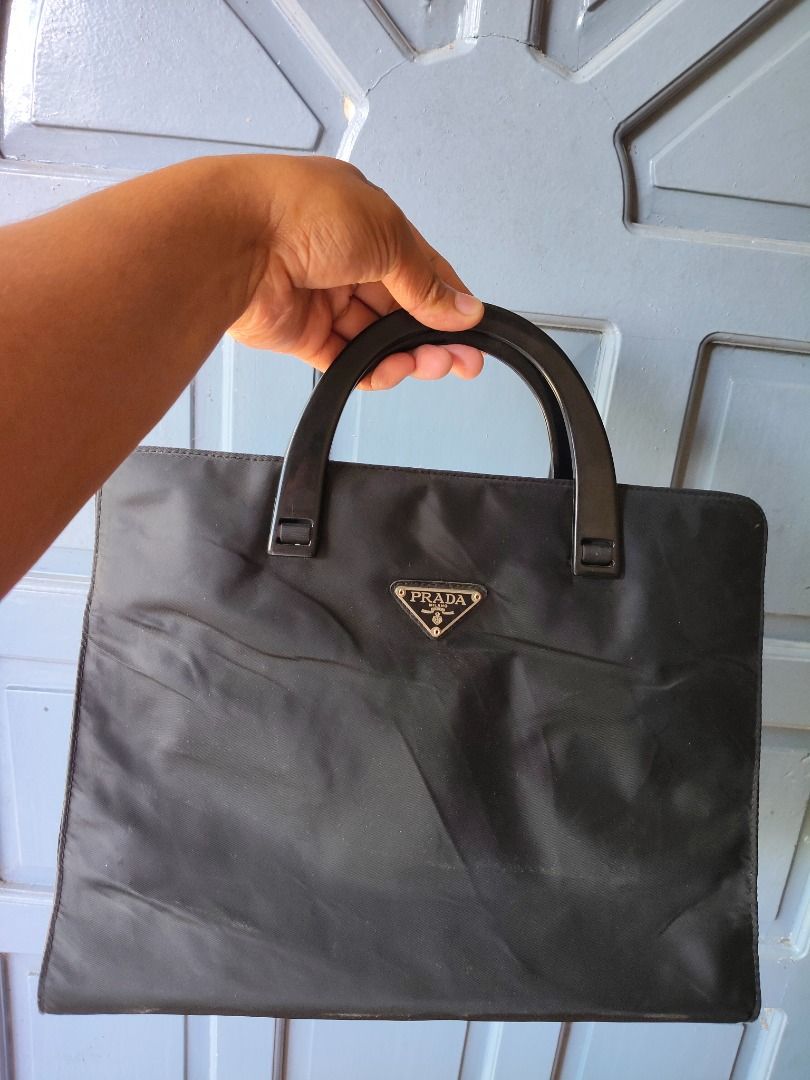 Prada Black Nylon Tote Bag (Category: Luxury Bags & Wallets) located in Caloocan City. Submitted by balizaclar77072 (Listing ID 1427453350, Image 1). Description: Black Prada tote bag. Features a top handle design with a zipper closure on the back. The interior includes a small pocket with a Prada label. The bag has a triangular Prada logo on the front. Made in Italy..