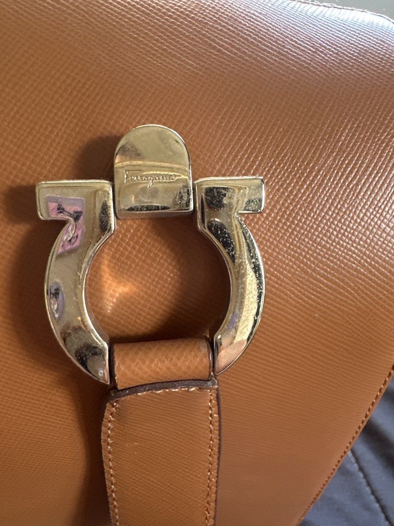 Salvatore Ferragamo Brown Leather Handbag (Category: Luxury Bags & Wallets) located in Cainta. Submitted by shopbyyna (Listing ID 1427342950, Image 2). Description: Main flaw yung asa pic. Pagawa niyo nalang Guaranteed original SALVATORE FERRAGAMO Gancini camel leather bag The interior of the bag shows a slight stain, while the exterior has a slight scuff. Despite this, the item remains in very good condition. 9cm x 24.5cm x 13cm.