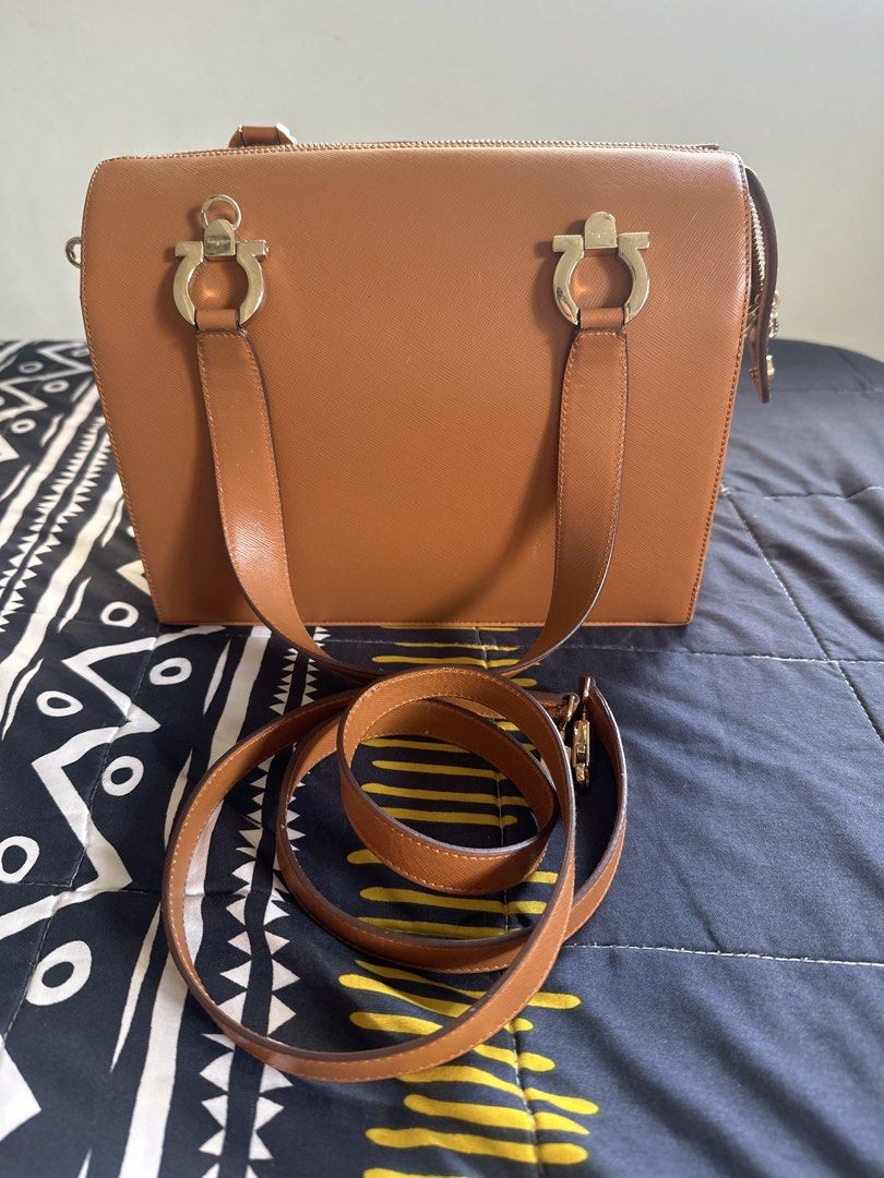 Salvatore Ferragamo Brown Leather Handbag (Category: Luxury Bags & Wallets) located in Cainta. Submitted by shopbyyna (Listing ID 1427342950, Image 1). Description: Main flaw yung asa pic. Pagawa niyo nalang Guaranteed original SALVATORE FERRAGAMO Gancini camel leather bag The interior of the bag shows a slight stain, while the exterior has a slight scuff. Despite this, the item remains in very good condition. 9cm x 24.5cm x 13cm.