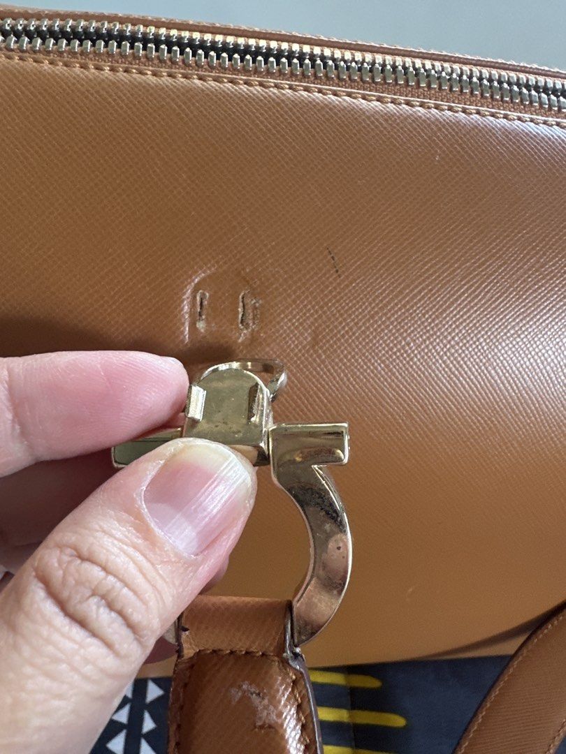 Salvatore Ferragamo Brown Leather Handbag (Category: Luxury Bags & Wallets) located in Cainta. Submitted by shopbyyna (Listing ID 1427342950, Image 3). Description: Main flaw yung asa pic. Pagawa niyo nalang Guaranteed original SALVATORE FERRAGAMO Gancini camel leather bag The interior of the bag shows a slight stain, while the exterior has a slight scuff. Despite this, the item remains in very good condition. 9cm x 24.5cm x 13cm.