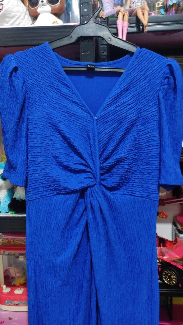 Shein Blue Textured Dress (Category: Dresses) located in Quezon City. Submitted by saffiyanicole23 (Listing ID 1427327772, Image 2). Description: Elegant blue dress with a textured fabric. Features a V-neckline and short sleeves. The dress has a knot detail at the waist, adding a stylish touch. The dress is hanging on a hanger..