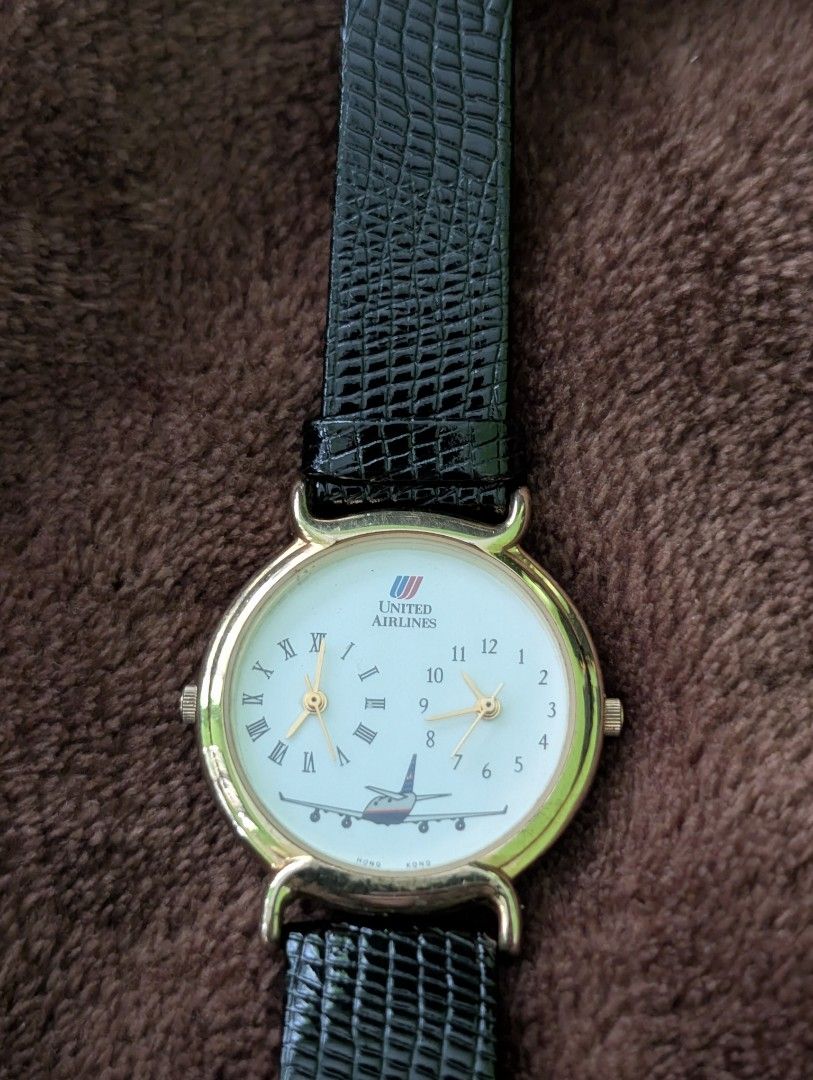 United Airlines Watch Dual (Category: Men's Watches) located in Muntinlupa City. Submitted by luckyfrogzone (Listing ID 1427379571, Image 2). Description: Watch features a gold-colored case and a black leather strap. The watch face displays the United Airlines logo and a picture of an airplane. It has two smaller dials and Roman numeral hour markers. The watch has a classic design with a textured leather strap..
