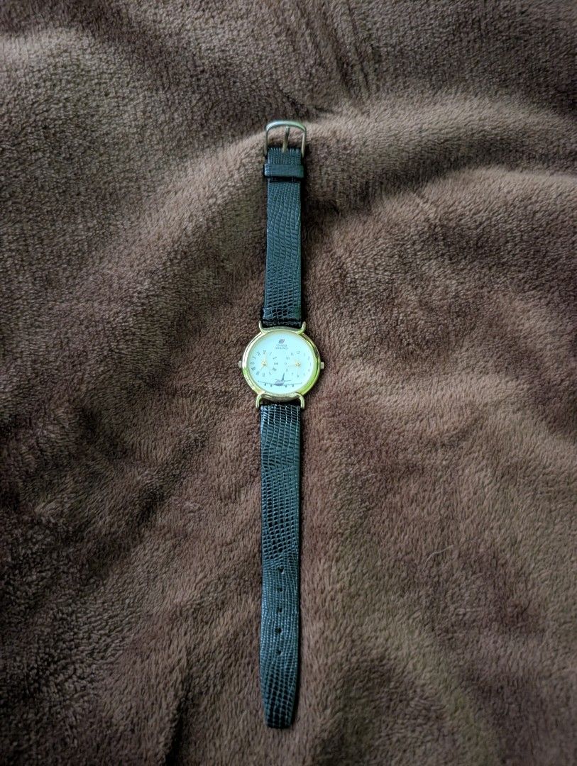 United Airlines Watch Dual (Category: Men's Watches) located in Muntinlupa City. Submitted by luckyfrogzone (Listing ID 1427379571, Image 1). Description: Watch features a gold-colored case and a black leather strap. The watch face displays the United Airlines logo and a picture of an airplane. It has two smaller dials and Roman numeral hour markers. The watch has a classic design with a textured leather strap..