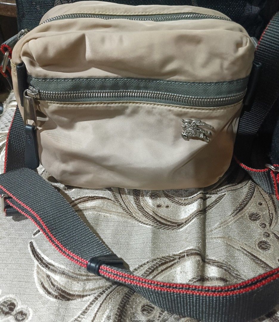 Burberry Crossbody Bag (Category: Luxury Bags & Wallets) located in Rizal. Submitted by judithtillo19 (Listing ID 1424288715, Image 1). Description: - Authentic Burberry crossbody bag - Beige nylon exterior - Silver-tone zipper and hardware - Fabric-lined interior with small pocket - Adjustable strap with red accents - Made in Italy.
