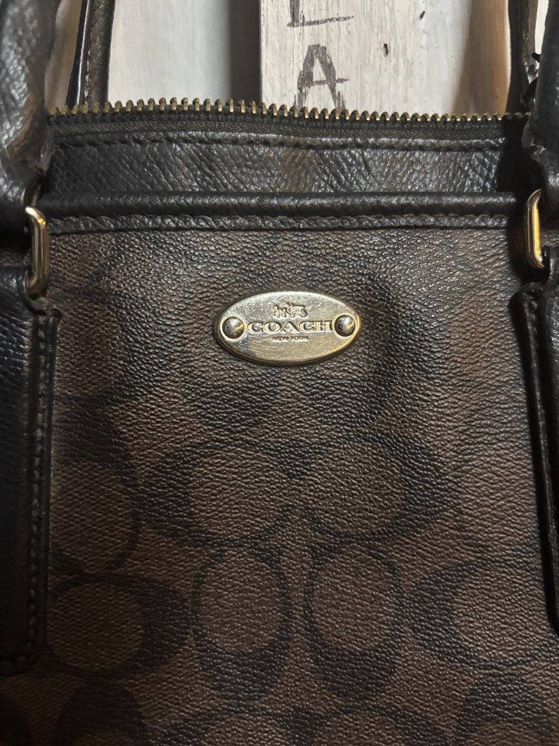 Coach Brown Signature Handbag (Category: Luxury Bags & Wallets) located in Quezon City. Submitted by tarphouse (Listing ID 1424326459, Image 2). Description: Authentic Coach handbag with a brown signature pattern. Features a top zipper closure, dual top handles, and an adjustable shoulder strap. The interior includes a Coach label. The bag has a classic design with a combination of brown and black colors. It has a metal Coach logo on the front..