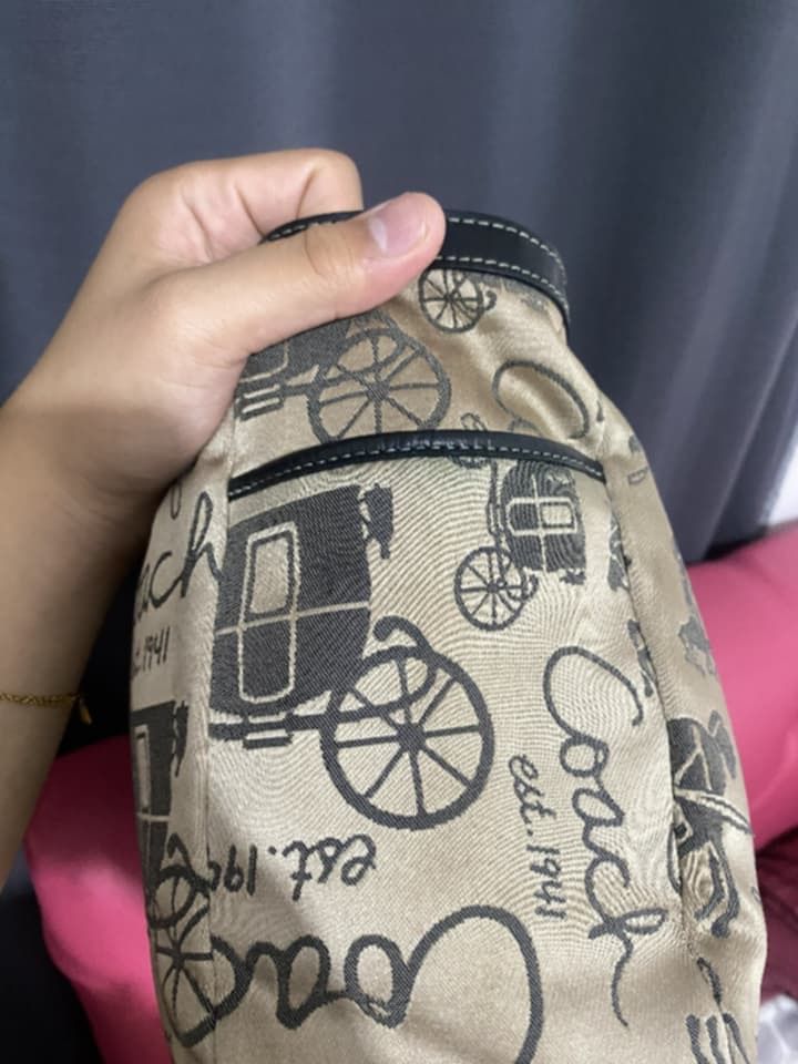 Coach Tote Bag with Carriage Print (Category: Luxury Bags & Wallets) located in Caloocan City. Submitted by cessang24 (Listing ID 1424323057, Image 2). Description: Coach tote bag featuring a classic carriage print. It has black leather handles and trim, with silver hardware accents. The bag has a beige background with a repeating pattern of carriages and the Coach logo..