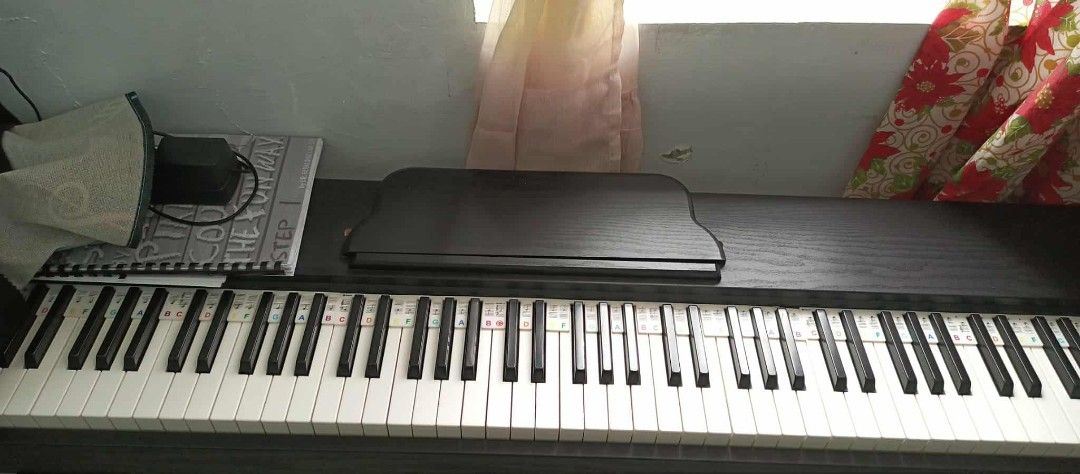Digital Piano with Music Sheet Cover (Category: Musical Instruments) located in Makati City. Submitted by livefire.73dc34 (Listing ID 1424182883, Image 3). Description: - Full-size digital piano - Features a digital display and control buttons - Includes music sheet cover - Comes with a power adapter - Keys are black and white.