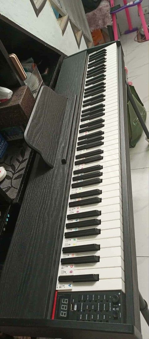 Digital Piano with Music Sheet Cover (Category: Musical Instruments) located in Makati City. Submitted by livefire.73dc34 (Listing ID 1424182883, Image 1). Description: - Full-size digital piano - Features a digital display and control buttons - Includes music sheet cover - Comes with a power adapter - Keys are black and white.