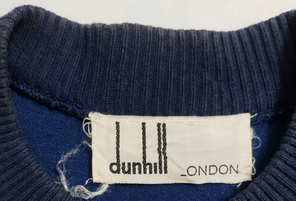 Dunhill London Velvet Jacket (Category: Coats, Jackets and Outerwear) located in Baguio. Submitted by luxeloom099 (Listing ID 1424337510, Image 3). Description: Navy blue velvet jacket from Dunhill London. Features a gold zipper and the Dunhill logo embroidered on the chest. The label indicates it's made in Switzerland with a blend of cotton and polyamide. Ribbed collar and cuffs. A stylish and classic piece. 26l x 20w.