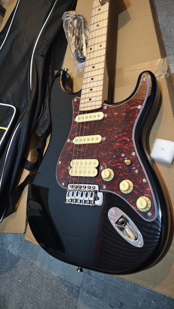 electric guitar (Category: Musical Instruments) located in Pasig City. Submitted by tupriomichaeljohn (Listing ID 1424179886, Image 2). Description: - Black Thomson electric guitar - Red tortoiseshell pickguard - Includes gig bag and cable - Maple neck - Rosewood fretboard - Thomson logo on headstock - Three pickups - Three control knobs - Gig bag with yellow stripe and Thomson logo.