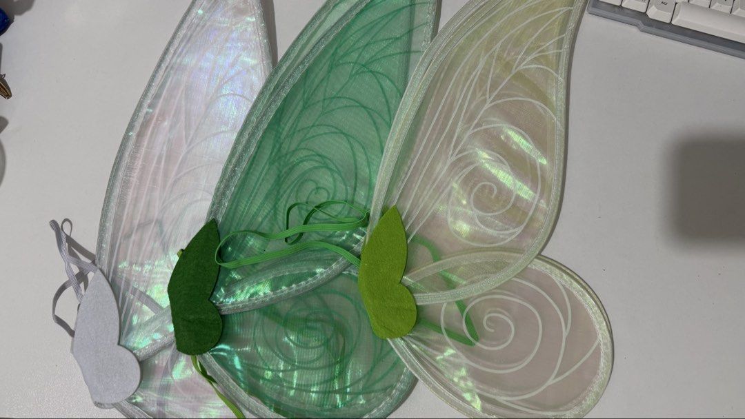 Iridescent Fairy Wings (Category: Other Accessories) located in Bauan. Submitted by berryhoon24 (Listing ID 1424314948, Image 1). Description: These fairy wings feature an iridescent design with a variety of colors. They have a green felt accent and elastic straps for easy wear. The wings are lightweight and suitable for costumes or dress-up. They are perfect for adding a touch of magic to any outfit. rfs: extra.