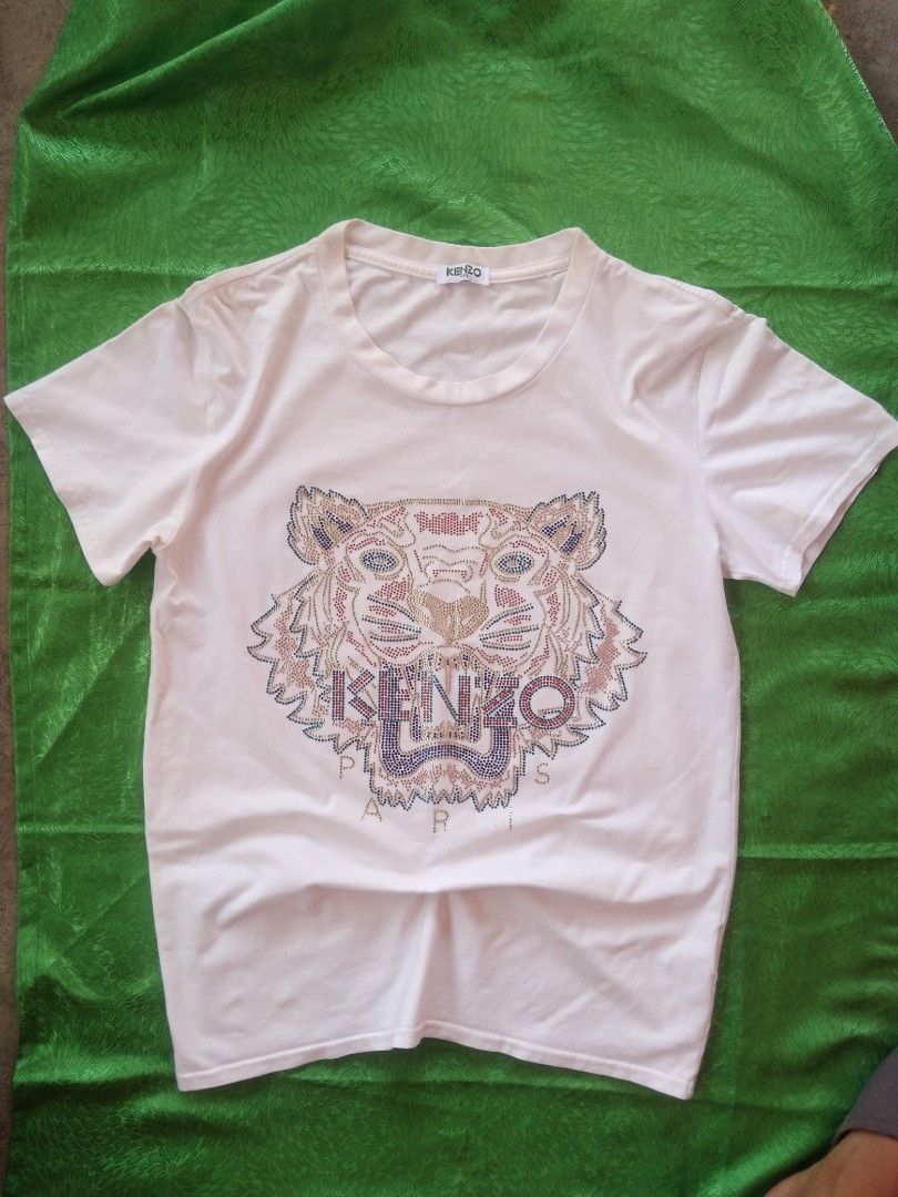 Kenzo Paris Tiger T-shirt (Category: Tshirts & Polo Shirts ) located in Jaen. Submitted by pitss06 (Listing ID 1424336998, Image 2). Description: - Kenzo Paris T-shirt - Features the iconic tiger design - white color - Made in Italy - Classic crew neck and short sleeves - Tiger design embellished with colorful studs.