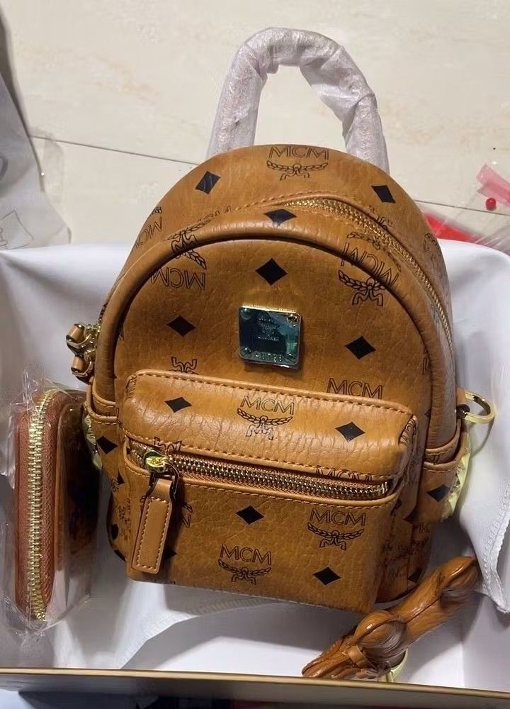 MCM Mini Backpack with Wallet & Charm (Category: Luxury Bags & Wallets) located in Makati City. Submitted by audreygatchalian (Listing ID 1424222759, Image 1). Description: - MCM mini backpack and matching wallet set. - Signature MCM logo pattern. - Front zippered pocket. - Top handle and adjustable straps. - Gold-toned hardware. - Comes with box. -Approx. 10x18x21cm.