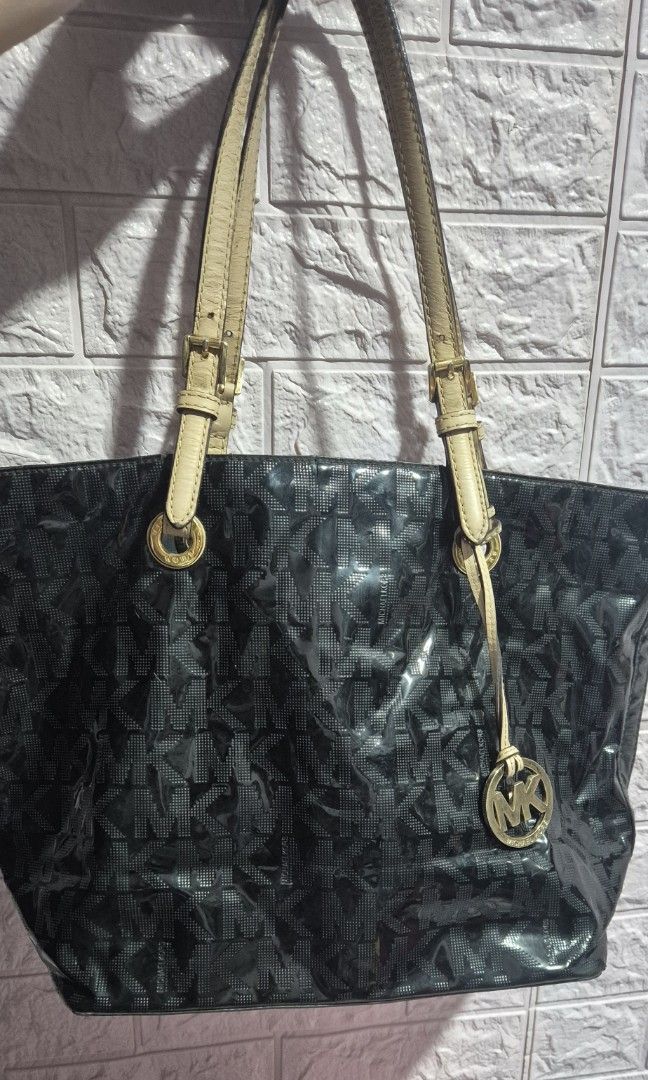 Michael Kors Black Tote Bag (Category: Tote Bags) located in Del Monte. Submitted by aabbuico (Listing ID 1424170104, Image 1). Description: - Michael Kors black tote bag - Glossy finish with MK logo pattern - Beige leather straps - Gold-tone hardware - Includes MK logo charm - Spacious design - Ideal for everyday use.