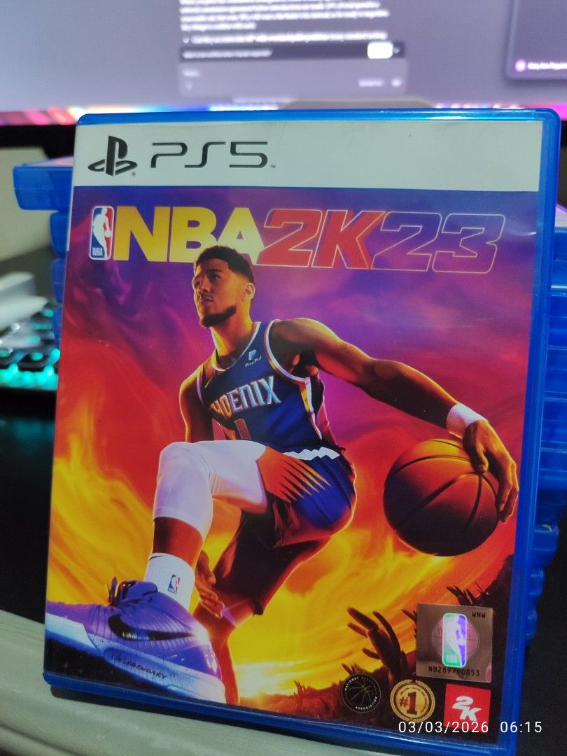 NBA 2K23 - PS5 (Category: PlayStation) located in Taguig. Submitted by mary6038 (Listing ID 1424336071, Image 1). Description: NBA 2K23 for PlayStation 5. Includes the game disc, a bonus card, and VC (Virtual Currency) codes. The game case is blue. The game features Devin Booker on the cover. Includes Tissot Tour Bonus..