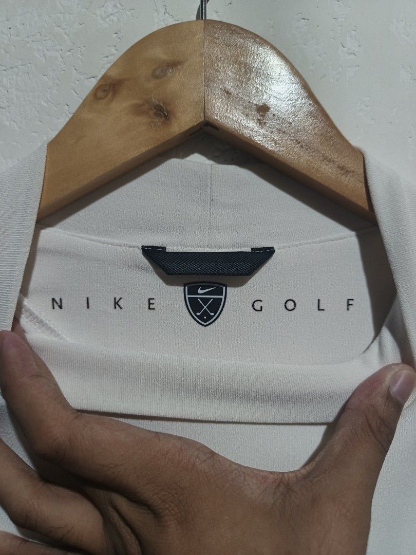 Nike Golf Mock Neck T-Shirt (Category: Tshirts & Polo Shirts ) located in Caloocan City. Submitted by mstrpreloved (Listing ID 1424316093, Image 3). Description: White Nike Golf mock neck t-shirt. Features a small Nike logo on the chest. The shirt has a mock neck collar and short sleeves. The tag indicates it is a men's shirt. Made in China..