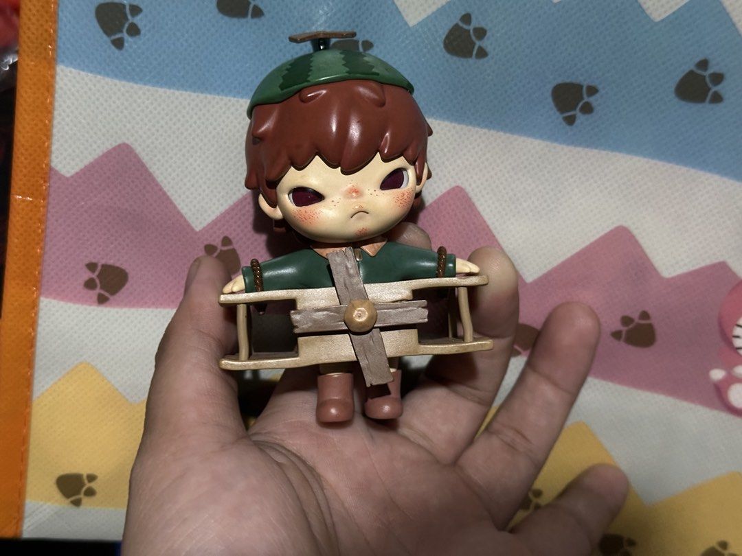 SIGNED HIRONO by Artist Lang (Category: Designer & Blind Box Toys) located in Pasig City. Submitted by j3tkoleks (Listing ID 1424233381, Image 1). Description: -Hirono Figure from Pop Mart - Features a boy design - Brown hair and green watermelon hat - Green shirt - Includes a wooden airplane - Great for display or collection Signed by Lang.