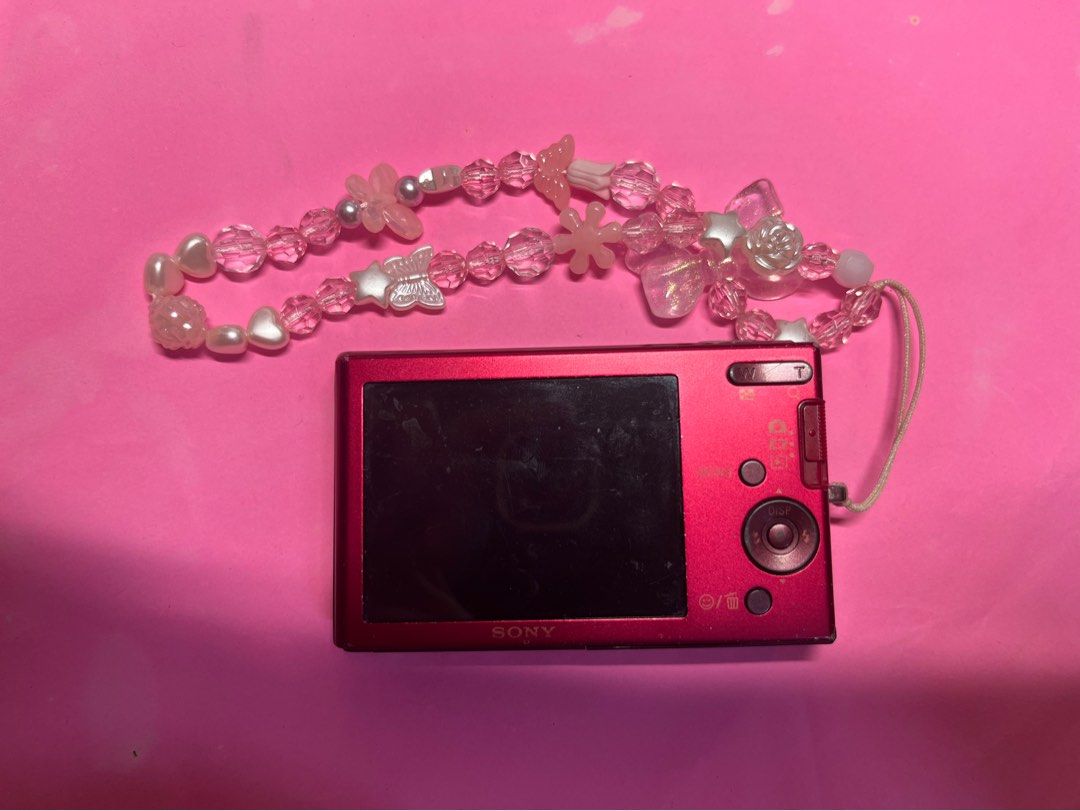 Sony Cyber-shot Digital Camera (Category: Cameras) located in Angeles City. Submitted by chaegyoung (Listing ID 1424280509, Image 2). Description: - Pink-red Sony Cyber-shot digital camera - Includes decorative beaded wrist strap - Wrist strap features butterfly and star charms - Camera has lens and flash -WORKING SO WELL - COMES WITH CHARGER -10.1 MEGA PIXEL .