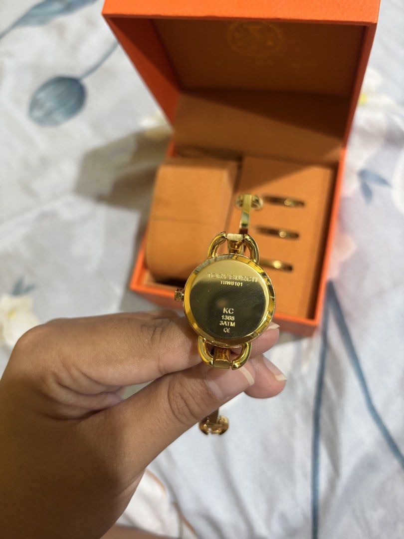 Tory Burch Ladies Bangle Watch with Rings (Category: Women's Watches) located in Manila. Submitted by elizabeth-declutter (Listing ID 1424168100, Image 3). Description: - Tory Burch ladies watch and ring set. - Gold-tone bracelet. - White dial with Tory Burch logo. - Includes three matching rings. - Comes with original orange box. - Perfect for a sophisticated look..