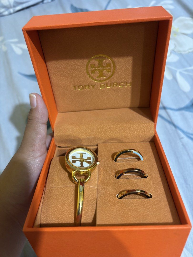 Tory Burch Ladies Bangle Watch with Rings (Category: Women's Watches) located in Manila. Submitted by elizabeth-declutter (Listing ID 1424168100, Image 2). Description: - Tory Burch ladies watch and ring set. - Gold-tone bracelet. - White dial with Tory Burch logo. - Includes three matching rings. - Comes with original orange box. - Perfect for a sophisticated look..