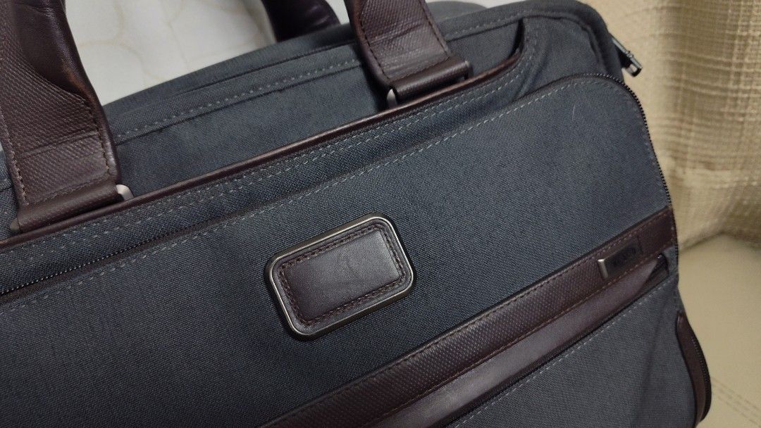 Tumi Briefcase anthracite (Category: Briefcases) located in Quezon City. Submitted by edwinvuru (Listing ID 1424196675, Image 2). Description: - Tumi briefcase - Sleek dark grey exterior with brown leather accents - Multiple compartments for organization - Padded interior - Detachable shoulder strap - Secure zipper closure - Includes luggage tag - Features metal Tumi logo.